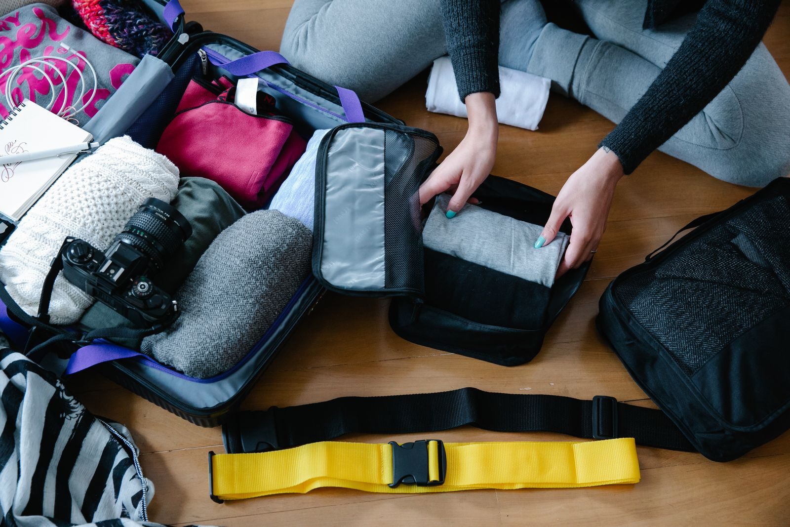 Hands packing clothes, a camera and gear into a bag for a spontaneous cruise