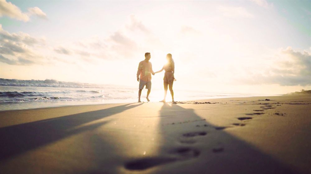 Couple walking hand in hand on a sunlit beach