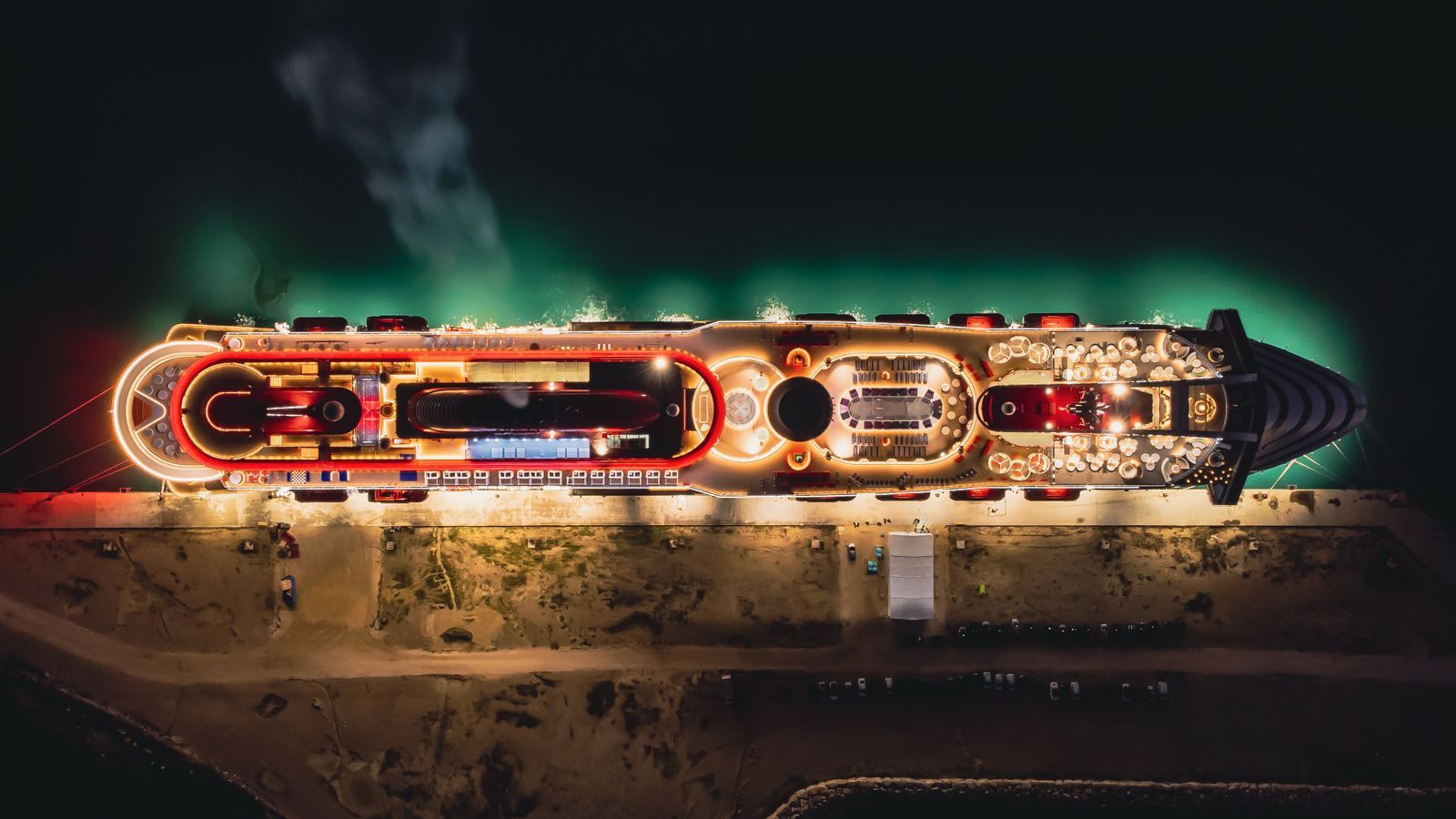 Aerial night view of a brightly lit cruise ship at the pier